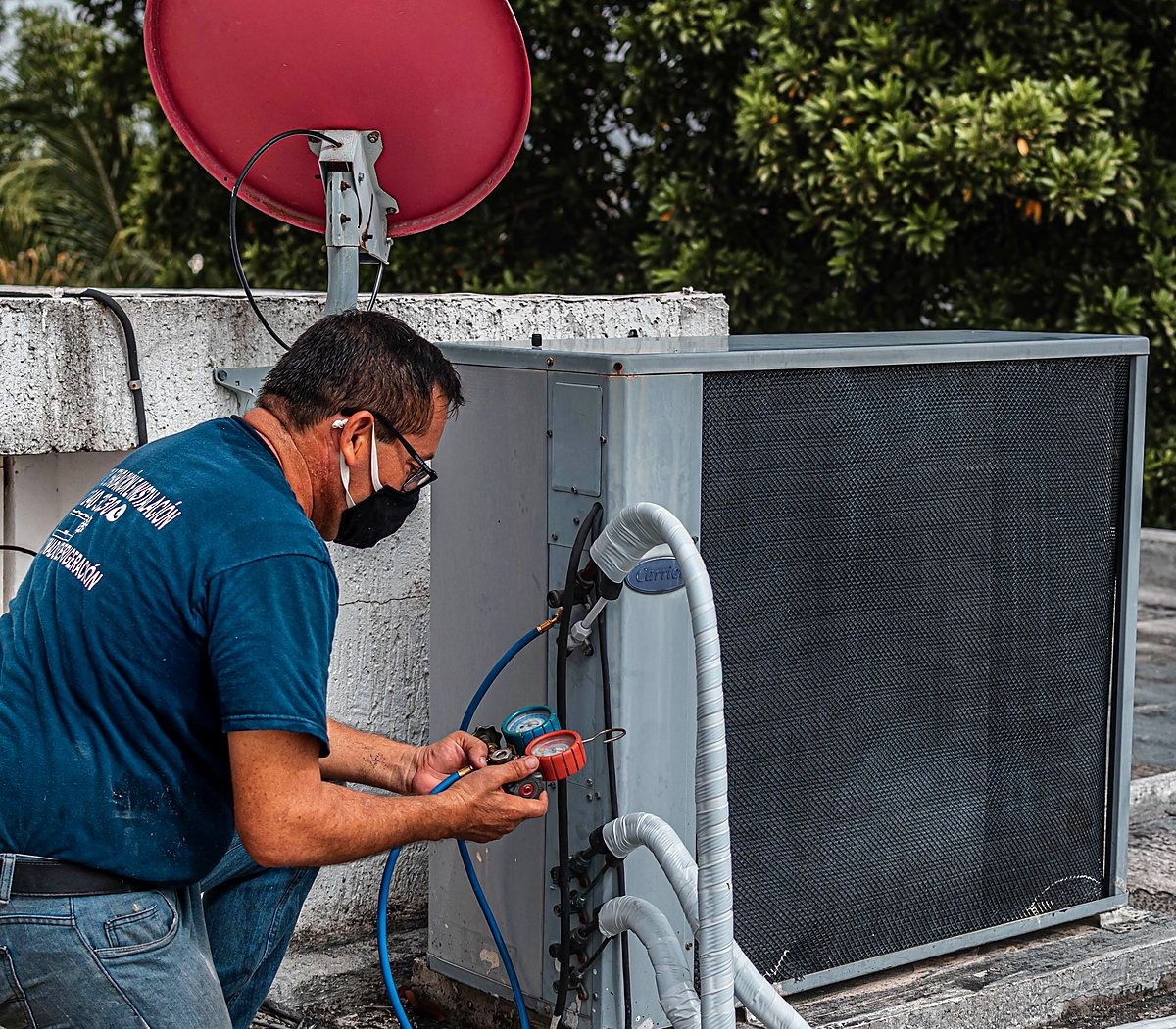 Técnico com máscara usando o manômetro em um equipamento externo